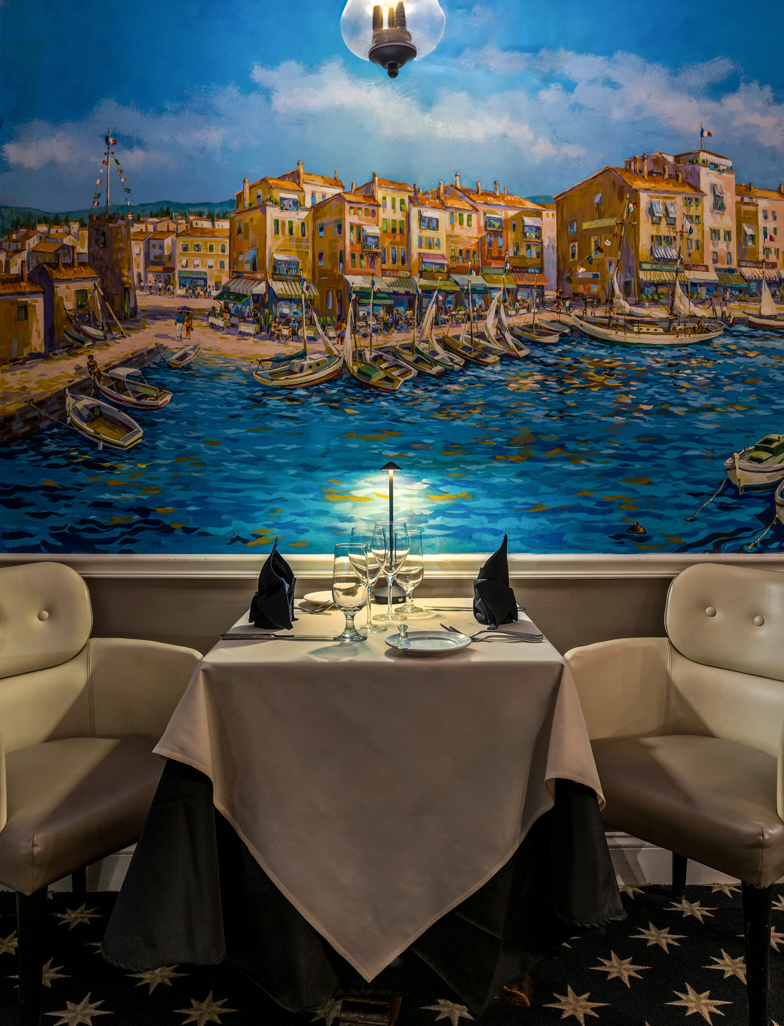 Romantic table for 2 against a beautiful mural in a restaurant in Newport RI.